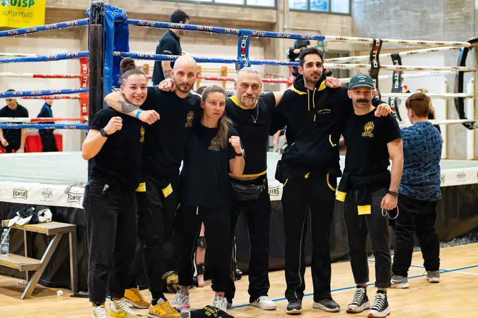 La squadra Combat Academy in magliette nere e giallo davanti a un ring